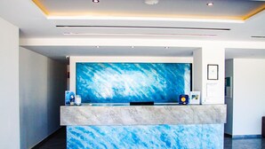 A reception desk with a large blue abstract painting, a marble counter, and a framed certificate on the wall. - Sunshine (Kos)