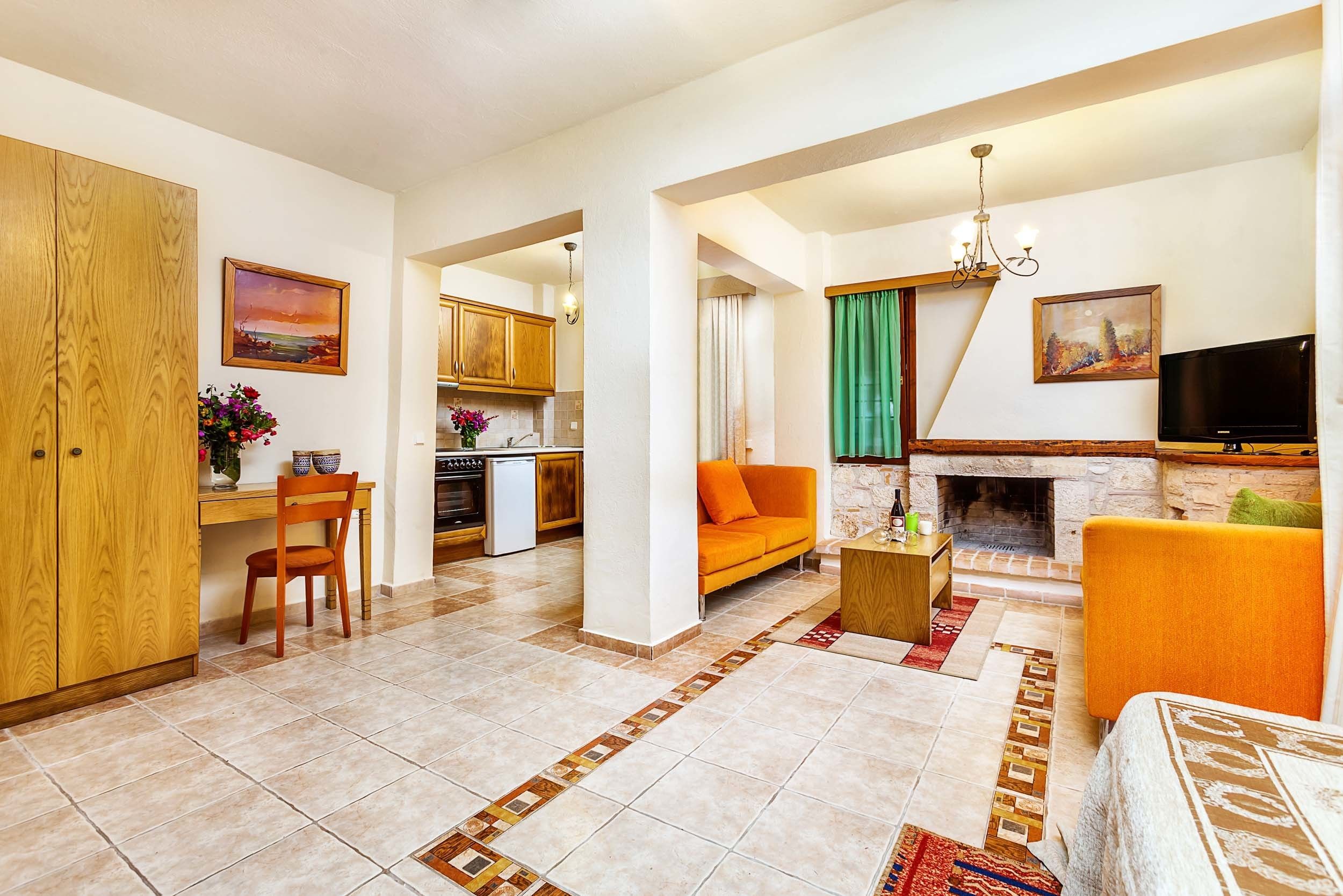 A spacious living area with a fireplace, a television, and a kitchen in the background.