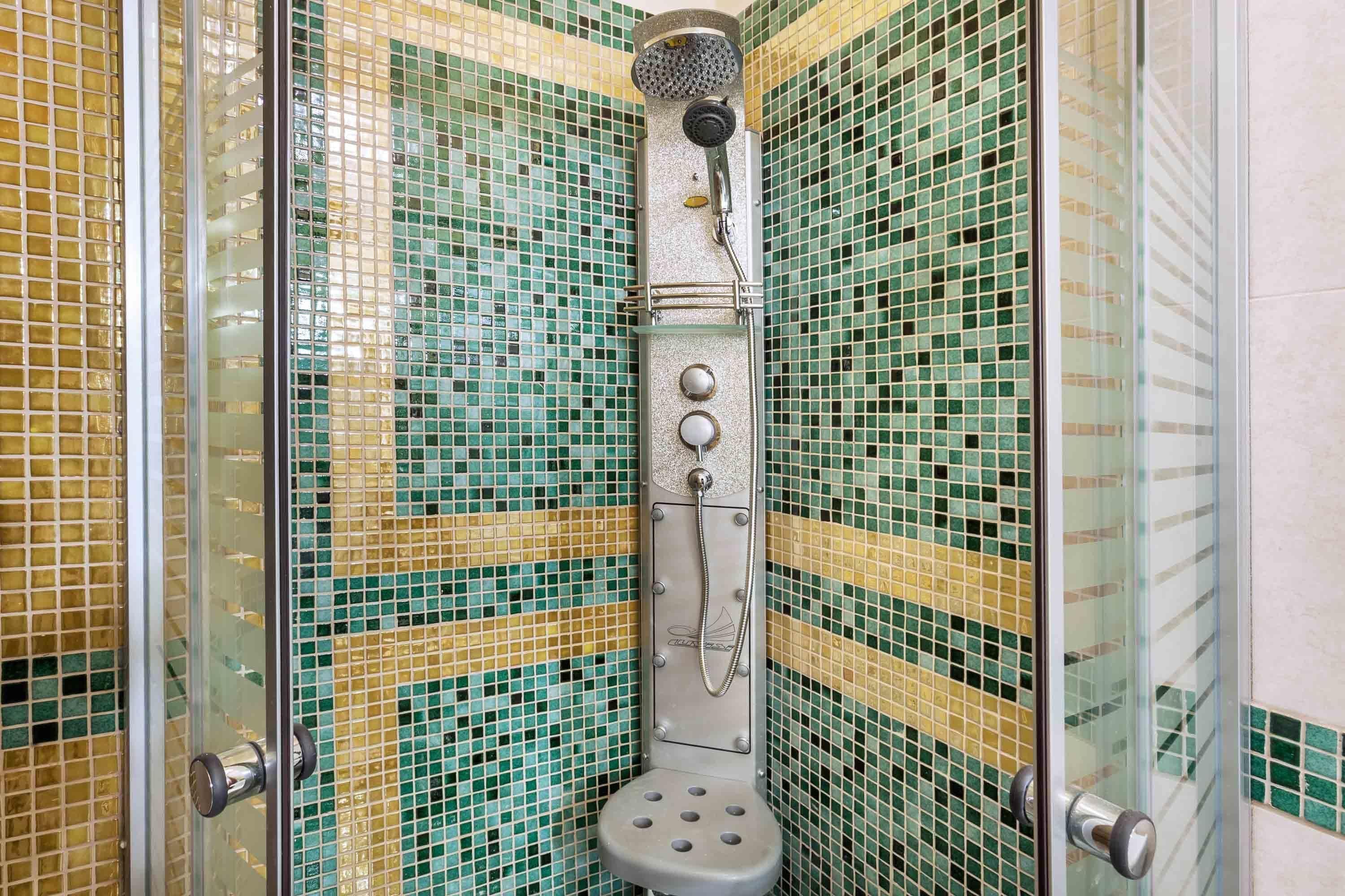A shower with a glass enclosure and a tiled wall.