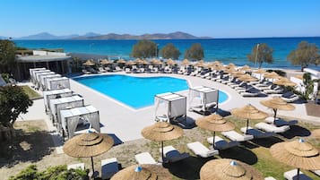 Zona junto a la piscina con sillones y sombrillas, piscina y vistas al mar y a las montañas.