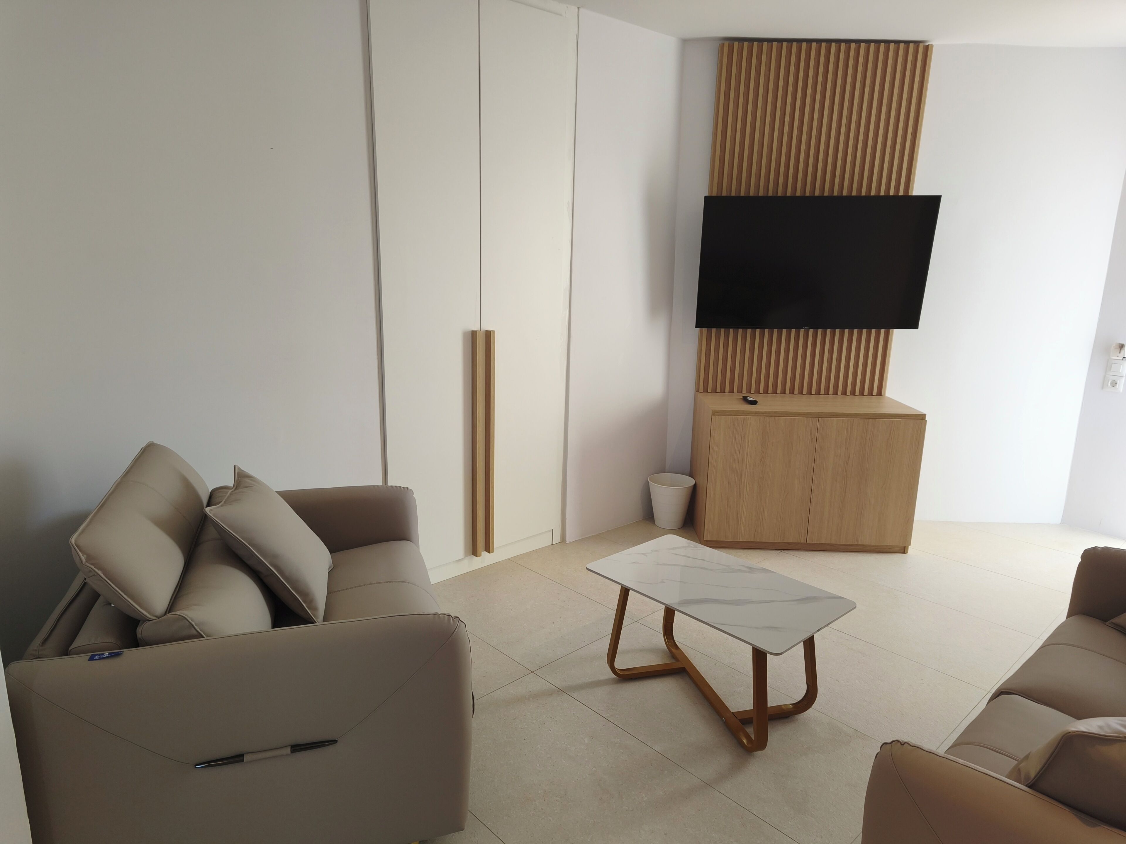 Una sala de estar moderna con un sofá, una mesa de centro, un televisor y un mueble.