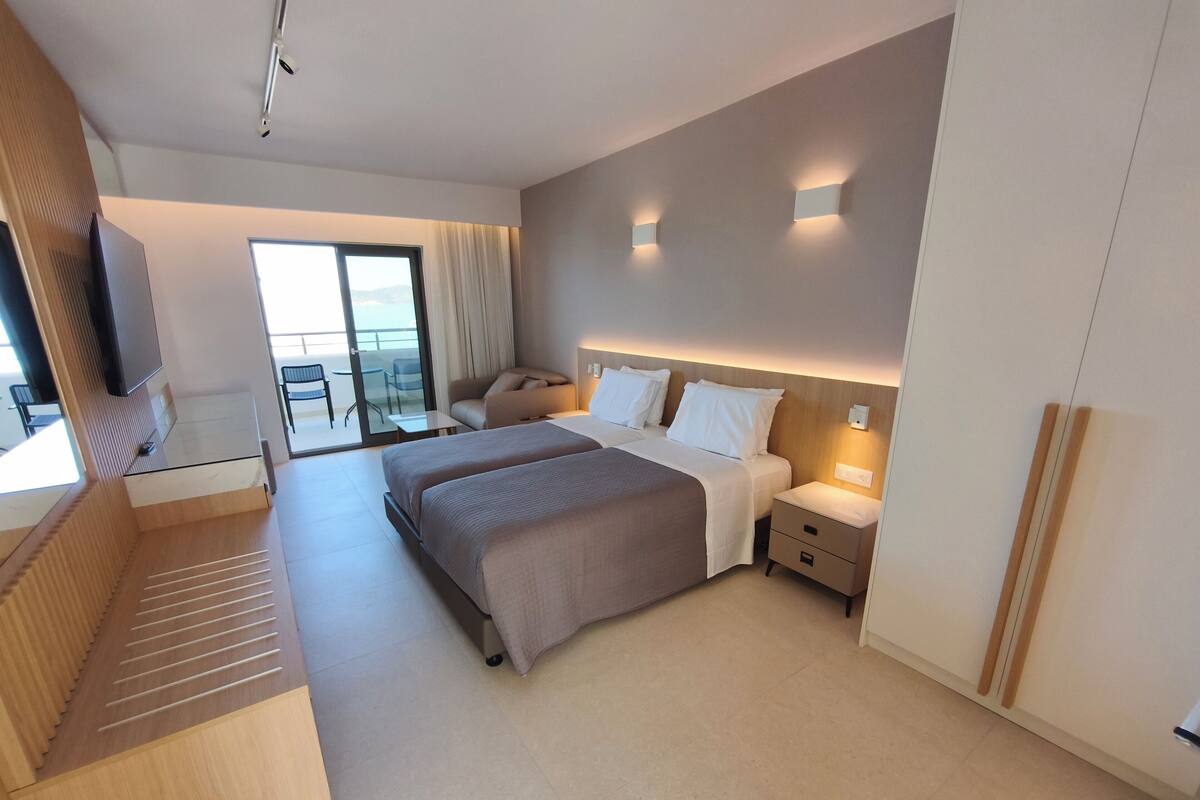 Una habitación de hotel moderna con una cama grande, un escritorio y un balcón con vistas.