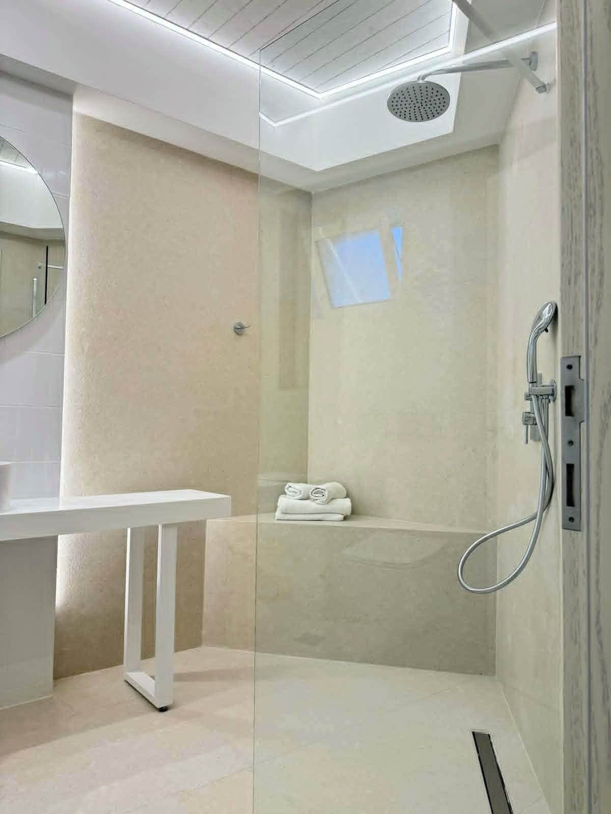 Een moderne badkamer met een douchecabine van glas, een witte wastafel en een plafondlamp.