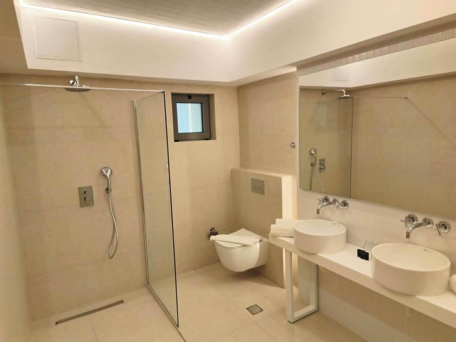 Ein modernes Badezimmer mit einer Duschkabine, einer Toilette und zwei Waschbecken.