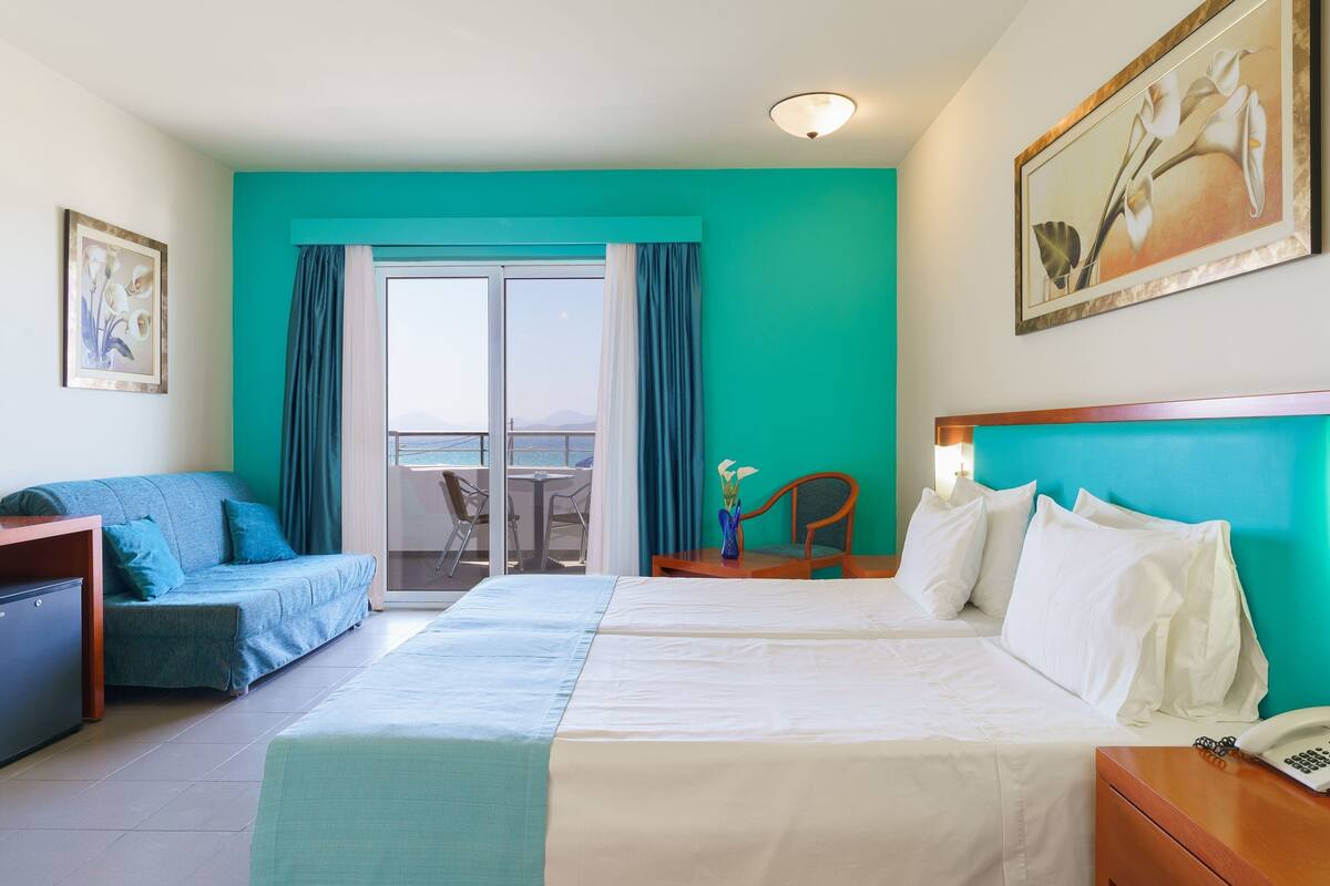 Habitación de hotel con cama, sofá, escritorio y vistas al exterior.