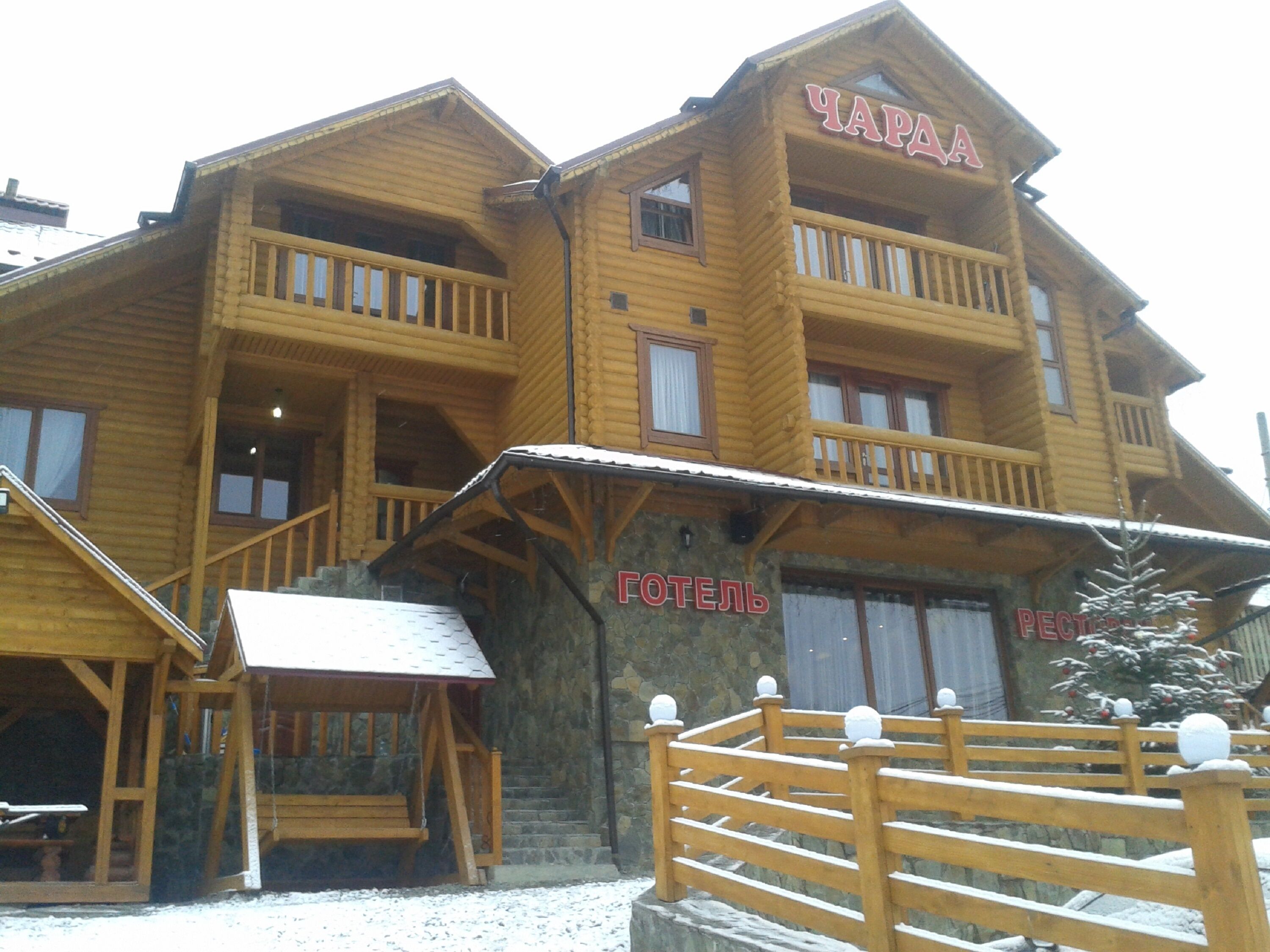 A wooden hotel with balconies and a sign reading "ЧАРА".