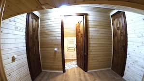 Una habitación con paredes y suelos de madera, con dos puertas de madera y un ventanal pequeño.
