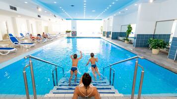 Una piscina techada, una piscina al aire libre de temporada, sombrillas
