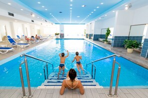 Una piscina techada, una piscina al aire libre de temporada, sombrillas