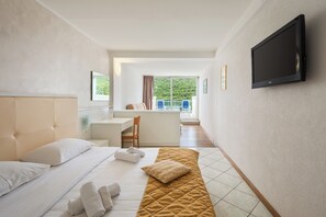 Habitación cuádruple estándar, balcón, vista parcial al mar | Caja de seguridad en la habitación, escritorio y cortinas blackout 