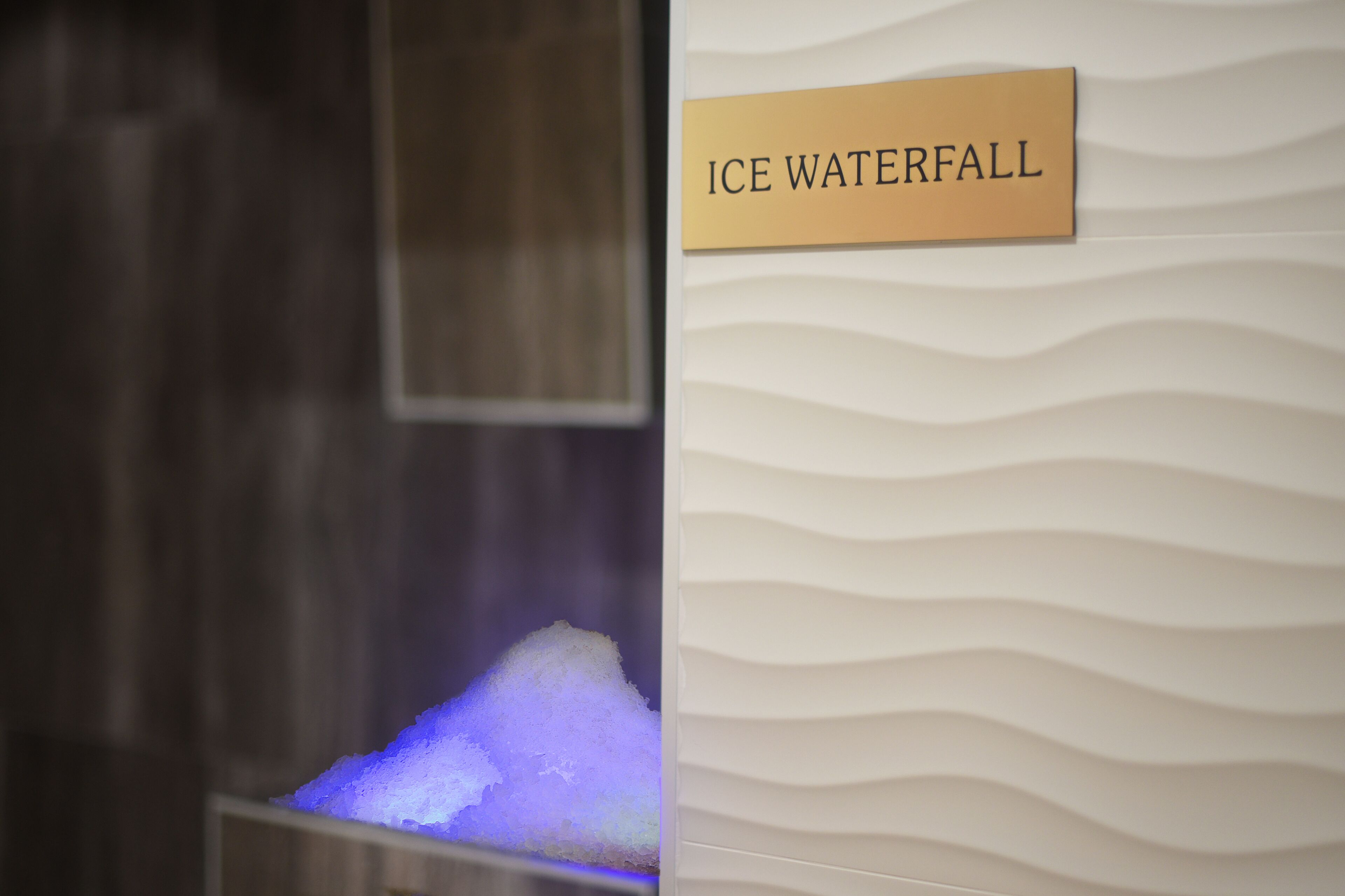 Ein Schild mit der Aufschrift 'ICE WATERFALL' und eine Wand mit einem Wellenmuster.