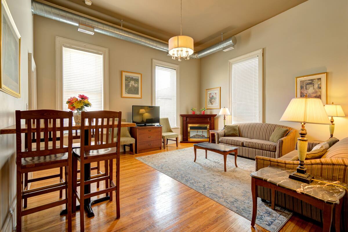 A living room with a wooden dining table, chairs, a sofa, a television, and a fireplace.