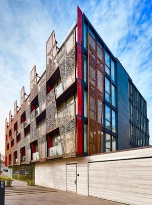 Stylish building with textured concrete and glass elements, featuring balconies and large windows.