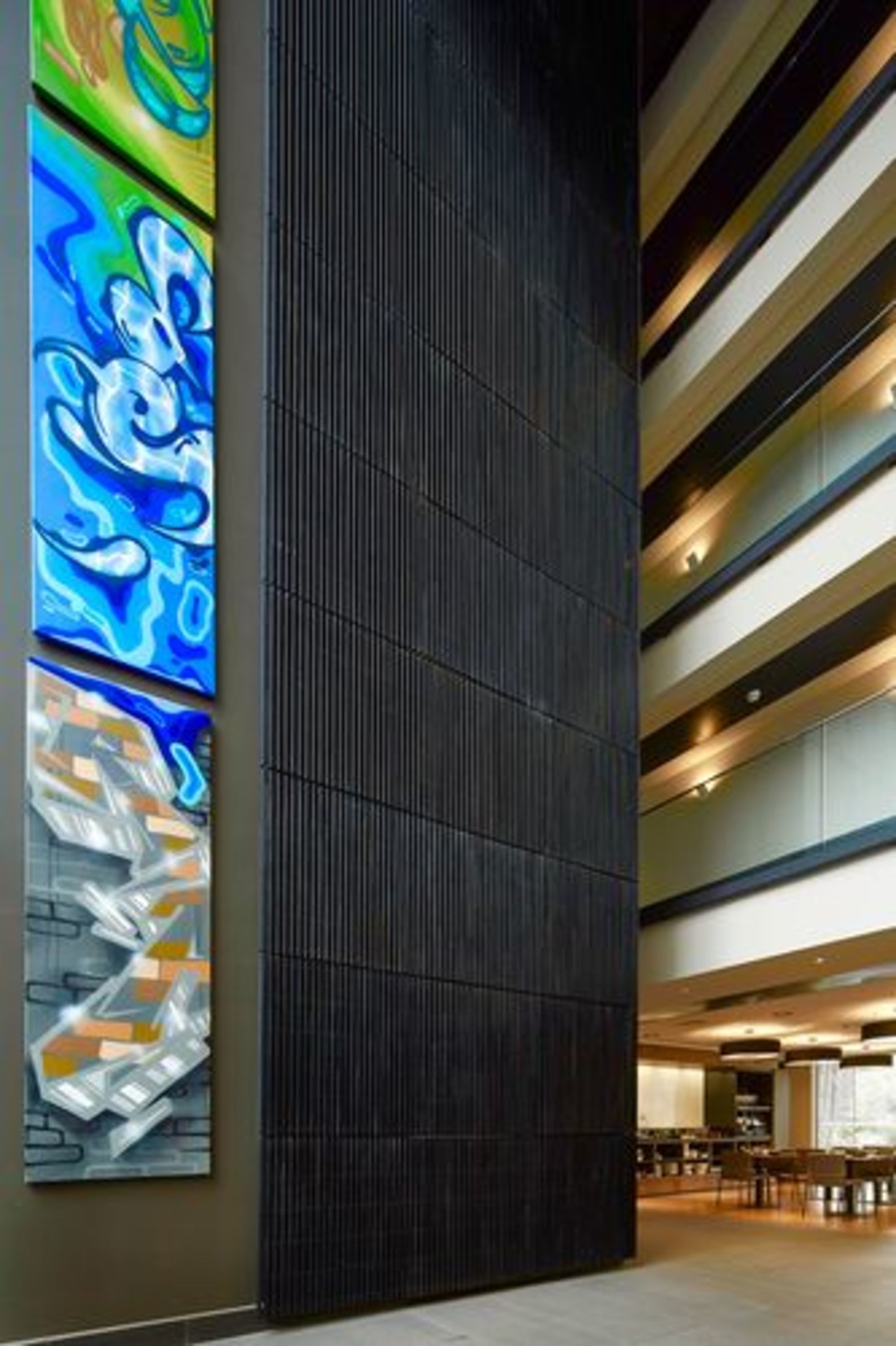 A modern interior with a dark vertical panel, horizontal lighting, and abstract art on the wall.