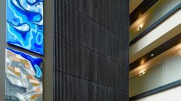 Een modern interieur met een donker verticaal paneel, horizontale verlichting en abstracte kunst aan de wand.