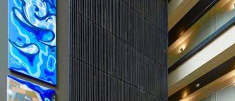 A modern interior with a dark vertical panel, horizontal lighting, and abstract art on the wall.