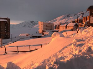 Paisaje nevado con edificios y una montaña al fondo.