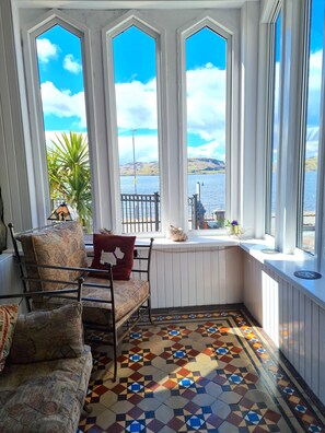 Un rincón acogedor con un sofá estampado, una mesita y vistas a un lago a través de amplias ventanas.