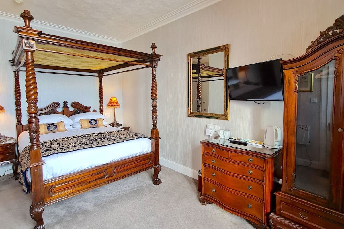 A four-poster bed with a wooden frame and a chandelier above.