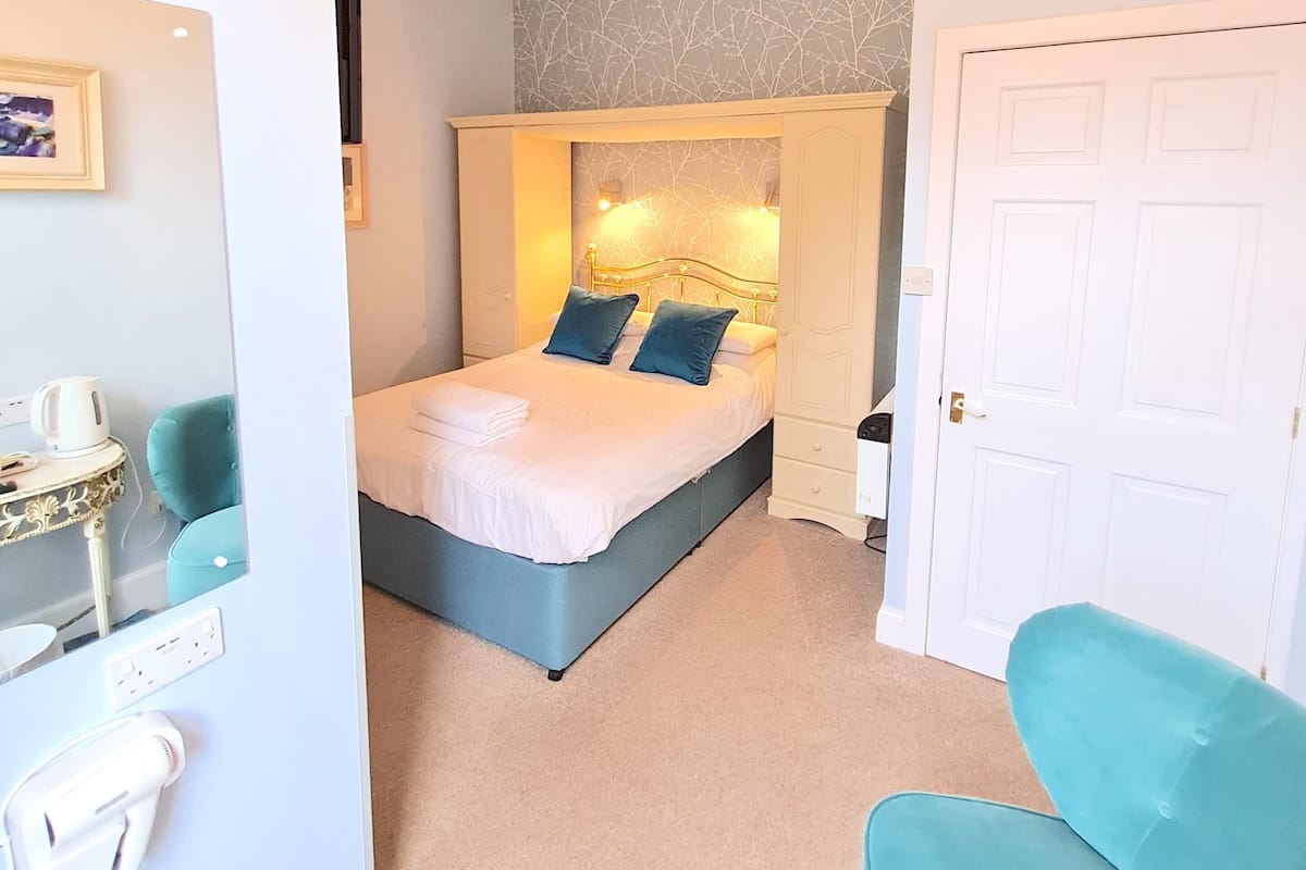 A bedroom with a bed, bedside tables, a wardrobe, a door, and a mirror.