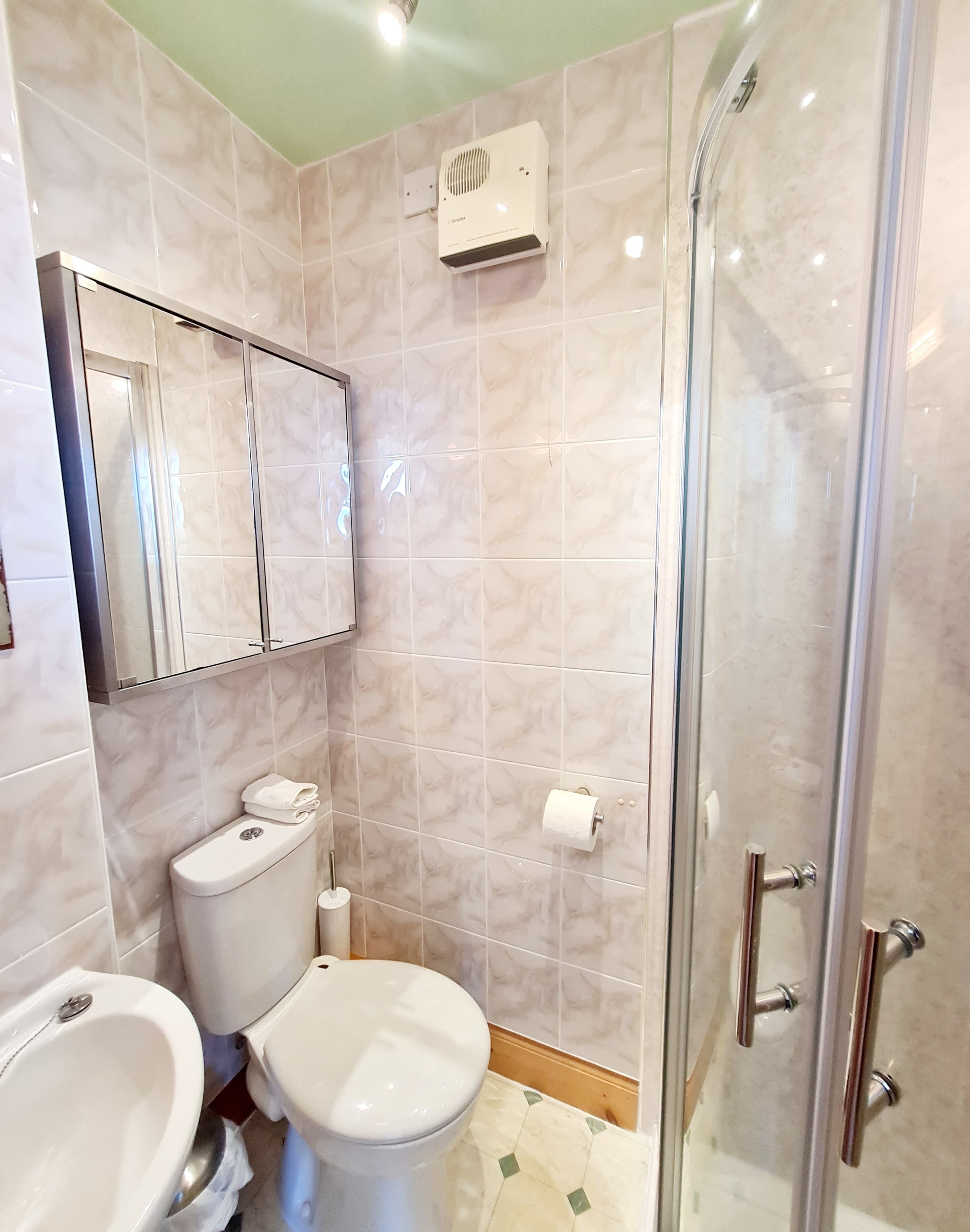 Un baño con inodoro, bidé y zona de ducha con mampara de vidrio.