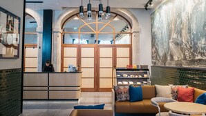 Een moderne lobby met een receptiebalie, een zithoek en een groot abstract schilderij.