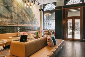 A modern lobby with a leather sofa, a large abstract mural, and a view of the street through glass doors. - The Editory House Ribeira Porto Hotel (Porto)