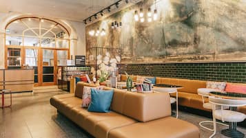 Un hall de hotel con diseño moderno, que incluye un sofá de cuero, una mesa de centro y una zona de bar.