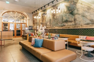Un hall de hotel con diseño moderno, que incluye un sofá de cuero, una mesa de centro y una zona de bar.