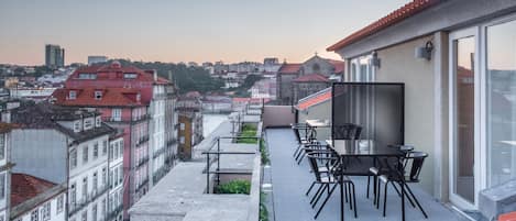 A rooftop terrace with outdoor seating, overlooking a cityscape with historic buildings and a river.