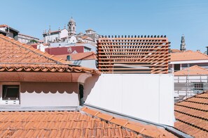 A rooftop with terracotta tiles, a white building with a window, and a metal structure. - The Editory House Ribeira Porto Hotel (Porto)