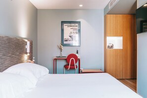 A modern bedroom with a large bed, a desk with a chair, a wooden wardrobe, and a framed picture on the wall. - The Editory House Ribeira Porto Hotel (Porto)