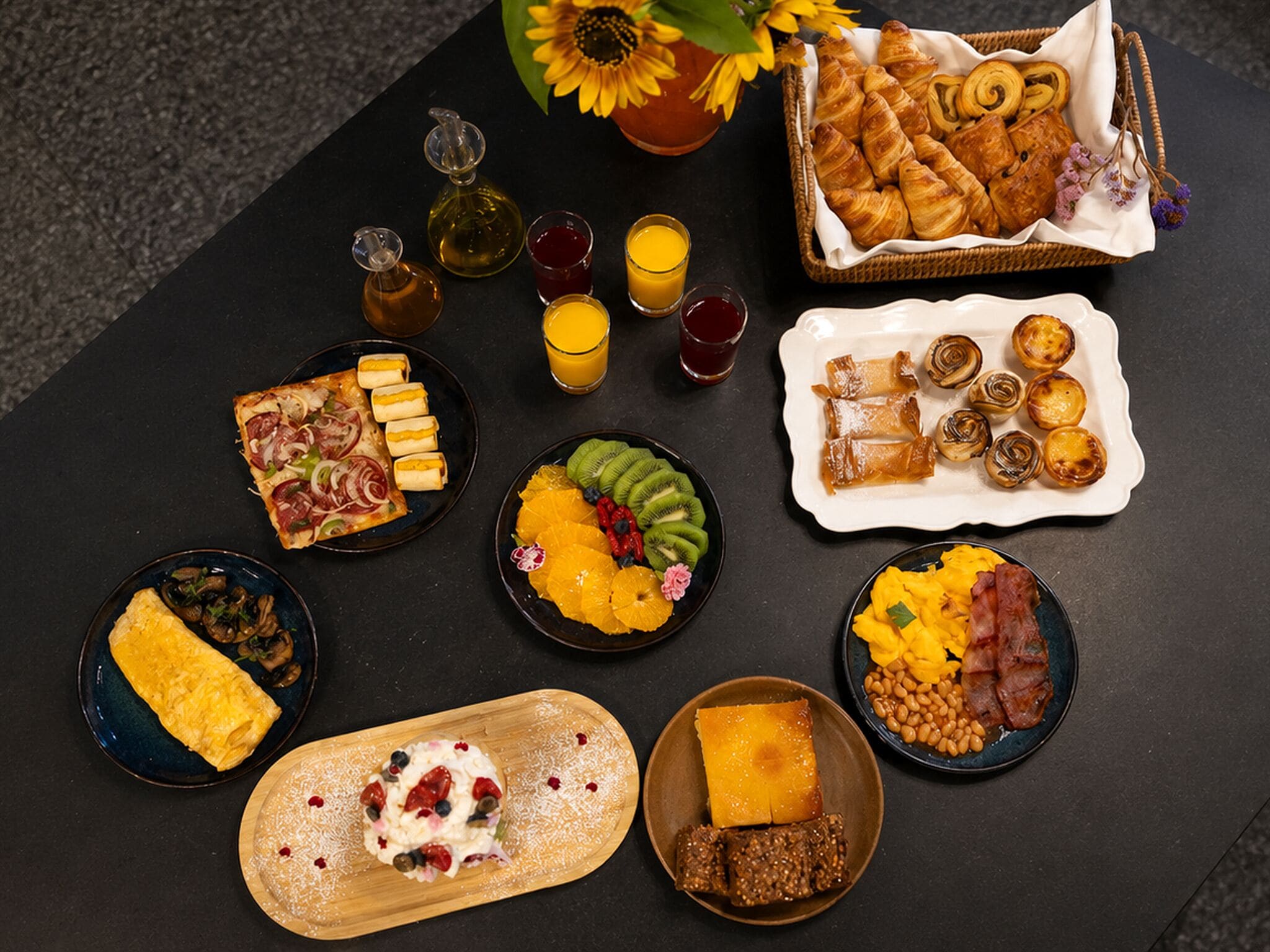 A variety of breakfast items including pastries, fruits, and beverages arranged on a table.