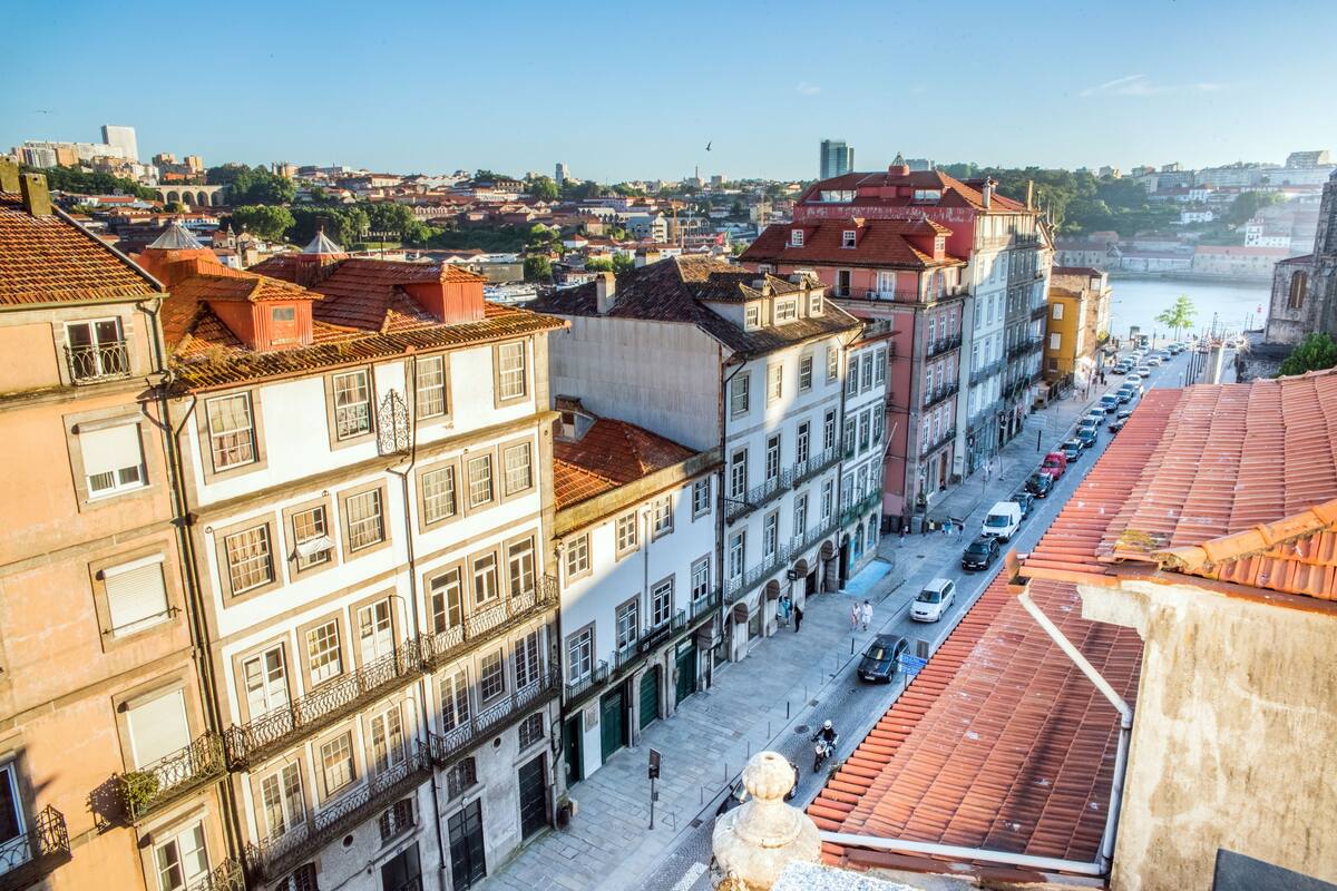 A street view of a historic city with buildings, a river, and a prominent church.