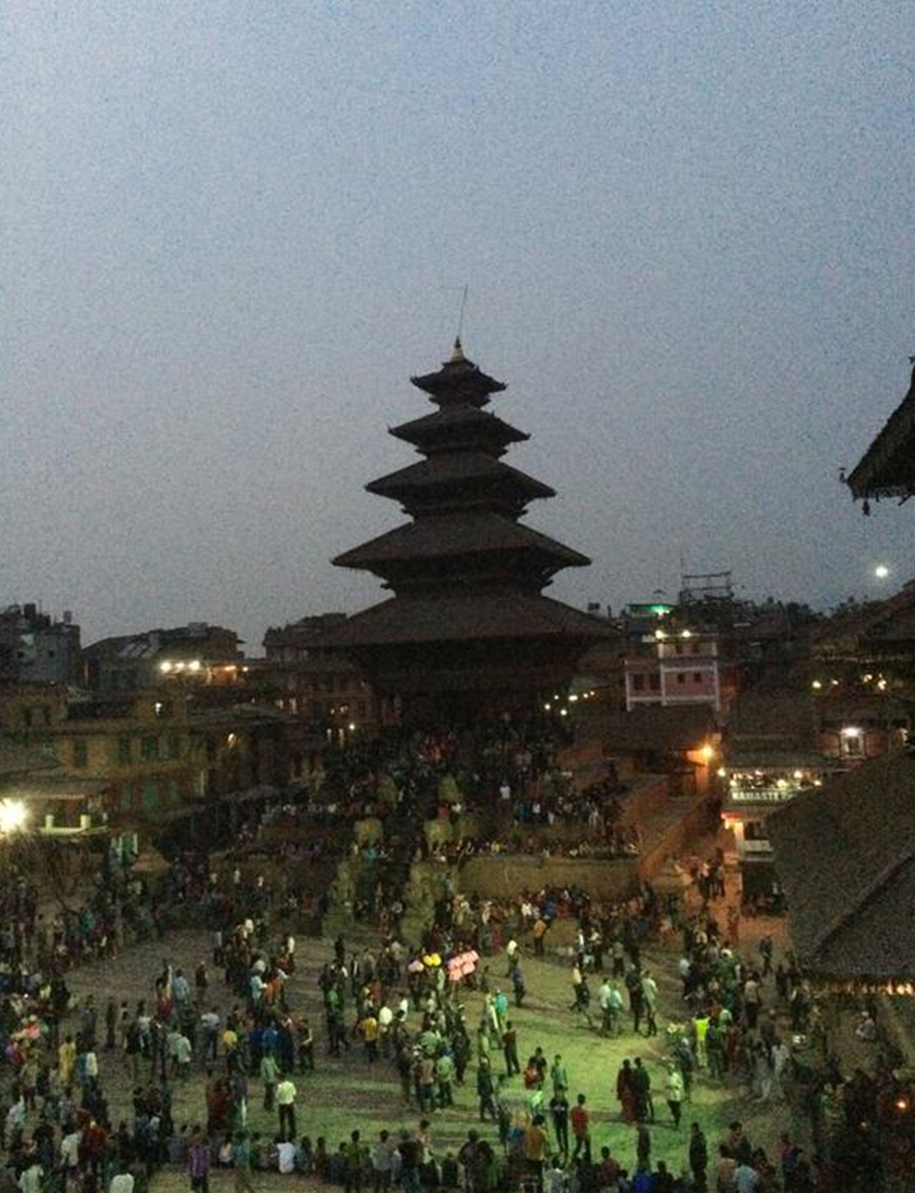 A traditional multi-tiered pagoda surrounded by a large crowd.