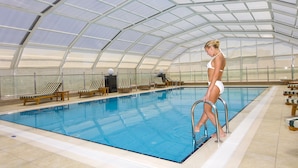 An indoor swimming pool with clear glass ceilings, lounge chairs, and a person standing by the pool. - Latanya Palm & Spa Airport Antalya (Antalya)
