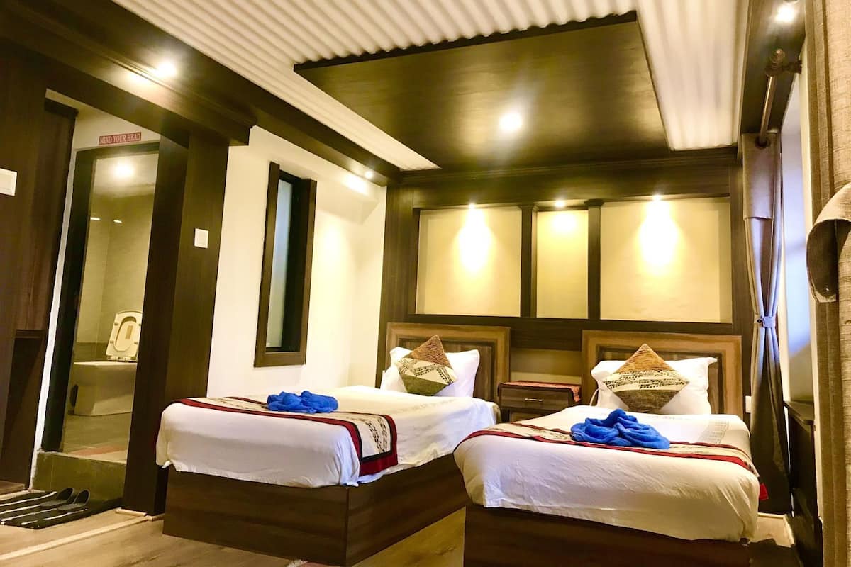 A hotel room with two beds, a mirror, a nightstand, and a bathroom visible through an open door.
