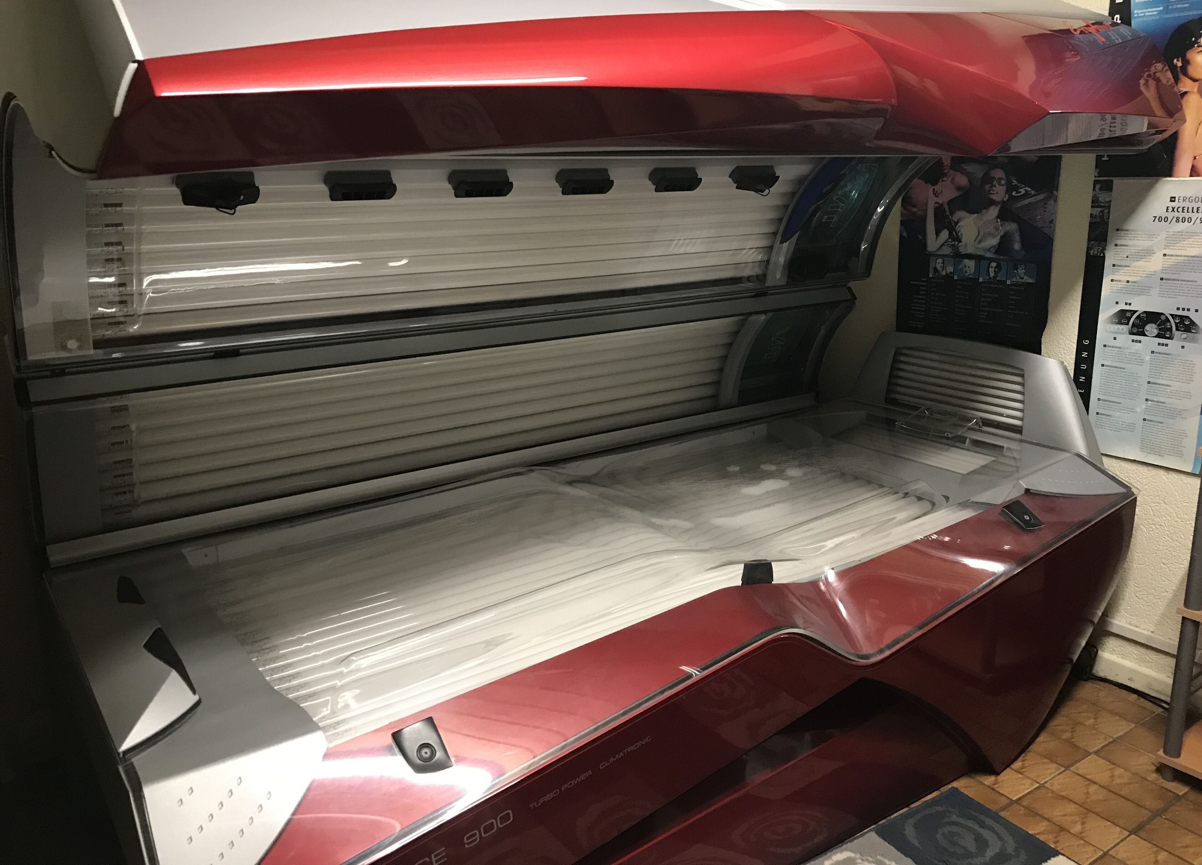 A red and white sauna with multiple benches and a control panel.