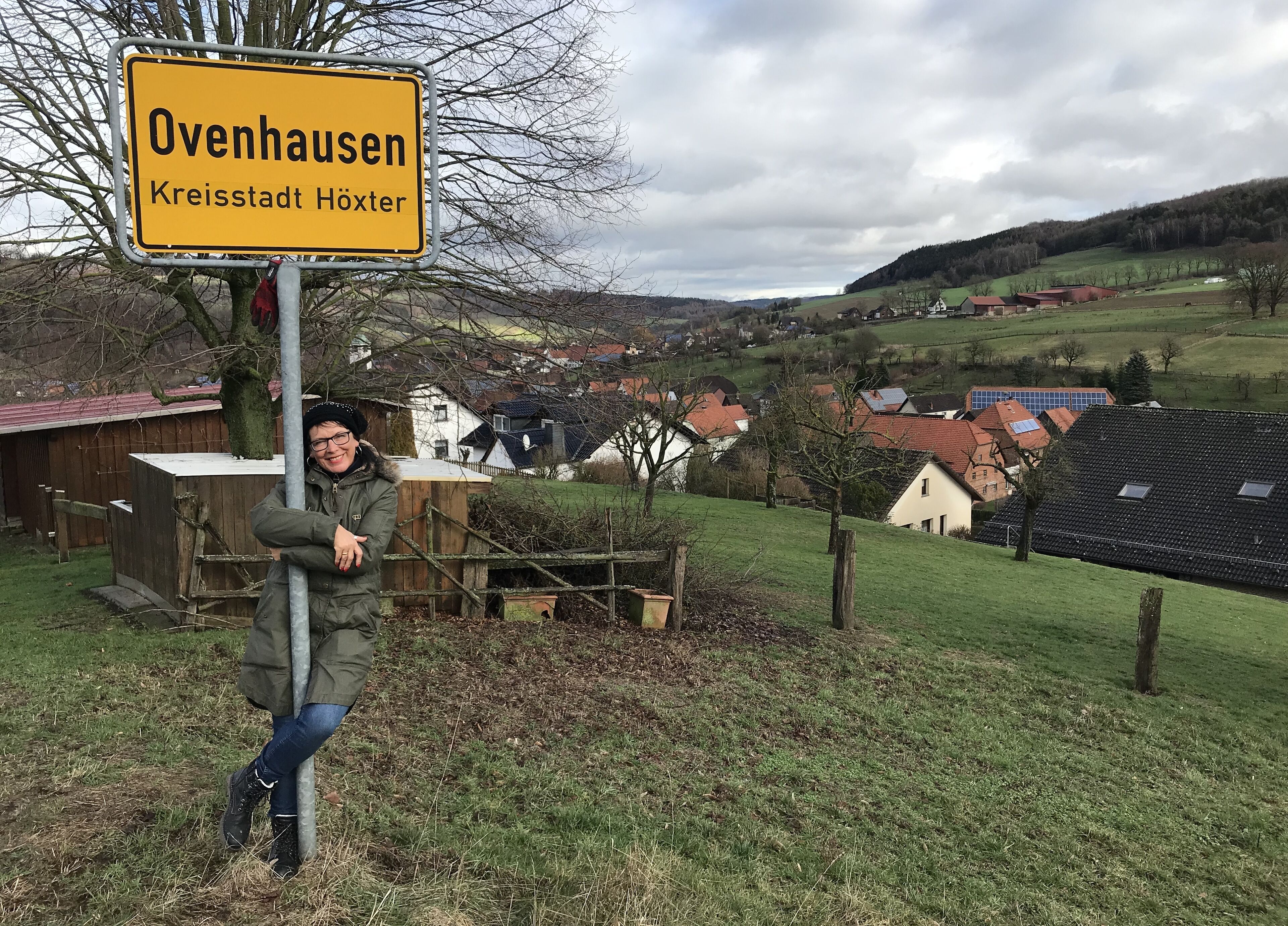 A sign for 'Ovenhausen' with a rural landscape in the background.