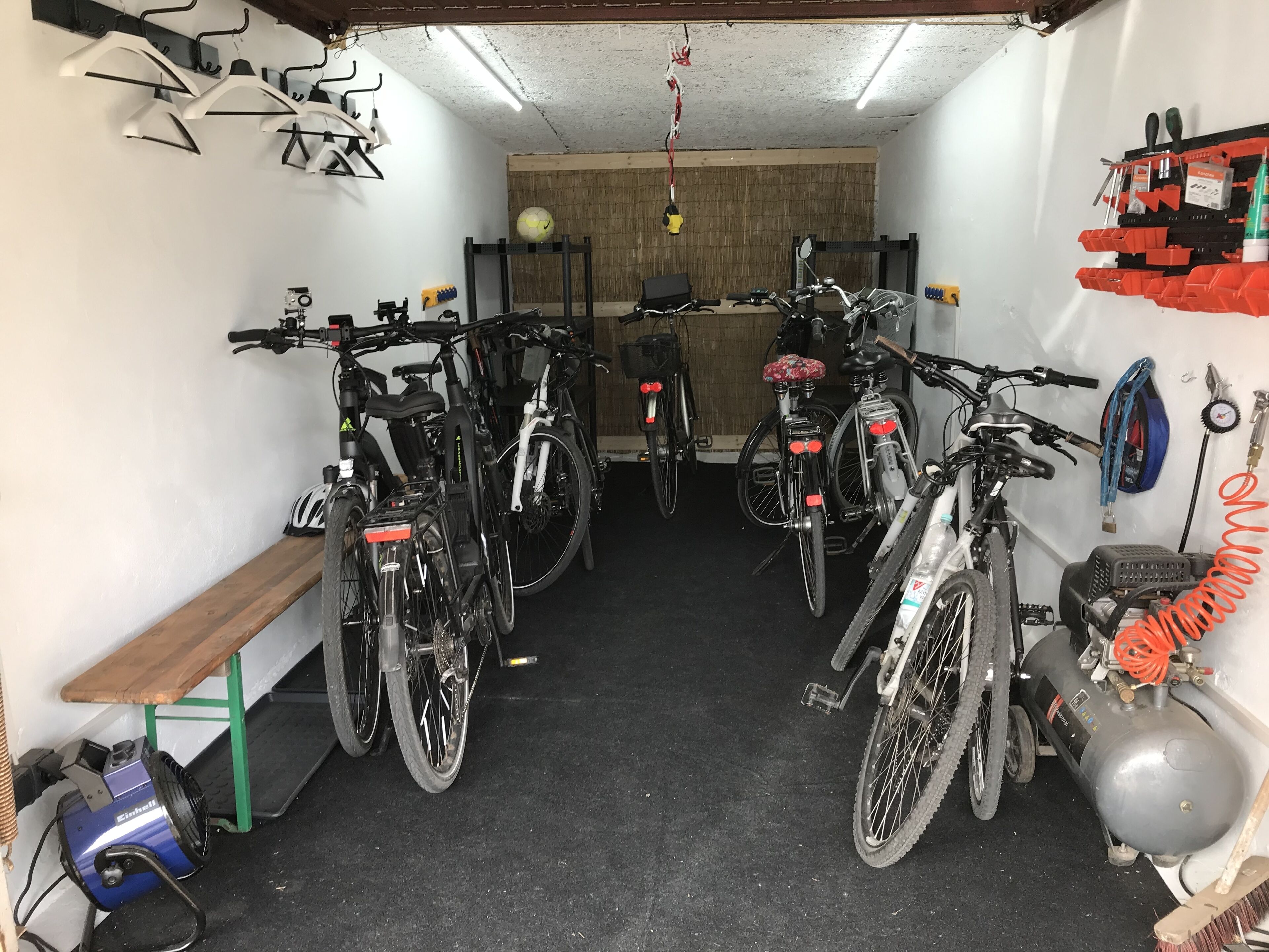 A garage with bicycles parked, a bench, and a tire pump.