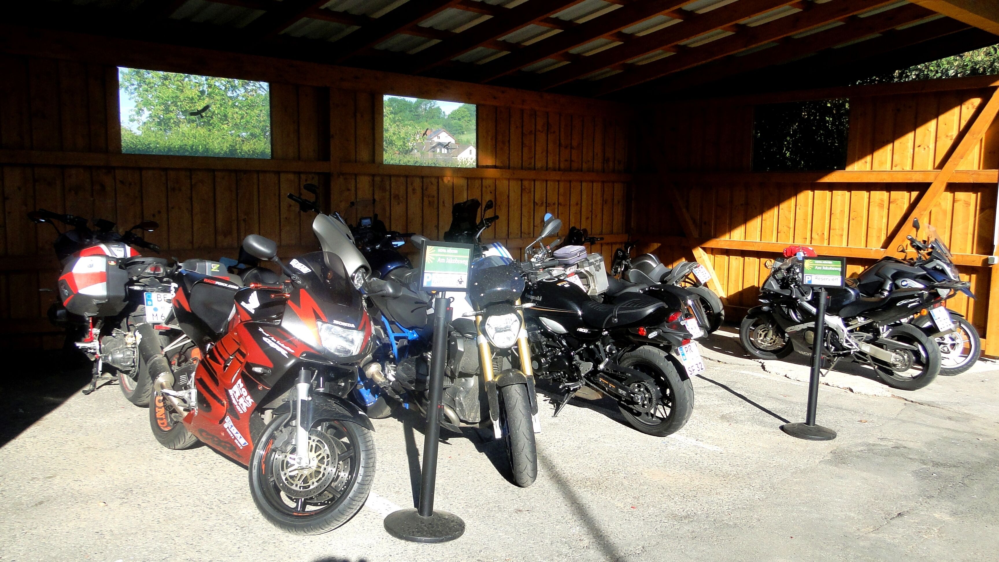 Un área de estacionamiento techada con varias motocicletas aparcadas en filas.