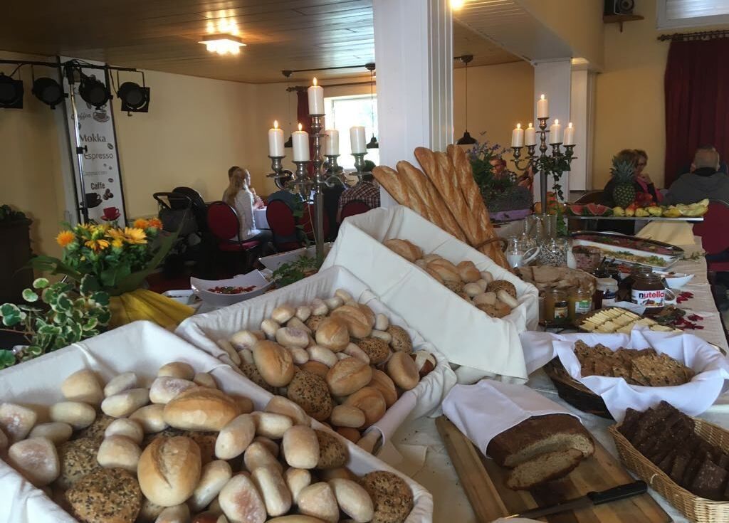 A buffet table with various breads and pastries, candles, and a menu board in a dining area.
