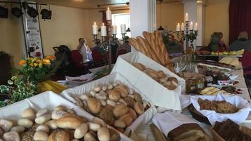 A buffet table with various breads and pastries, candles, and a menu board in a dining area.