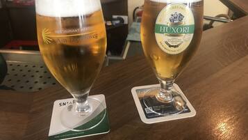 Dos vasos de cerveza sobre posavasos con logotipos, sobre una mesa de madera.
