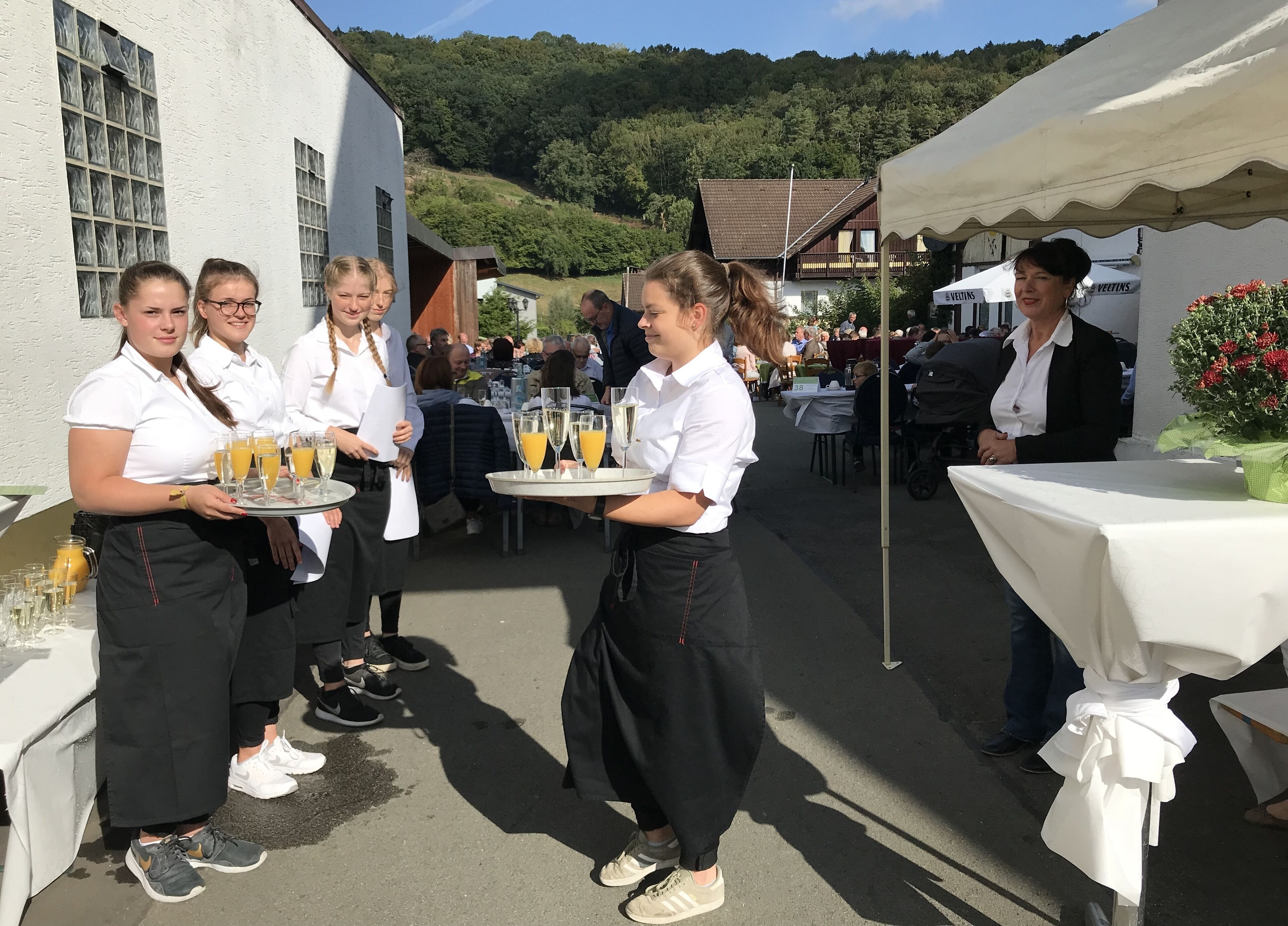 Servicemitarbeiter servieren Getränke bei einer Veranstaltung im Freien.