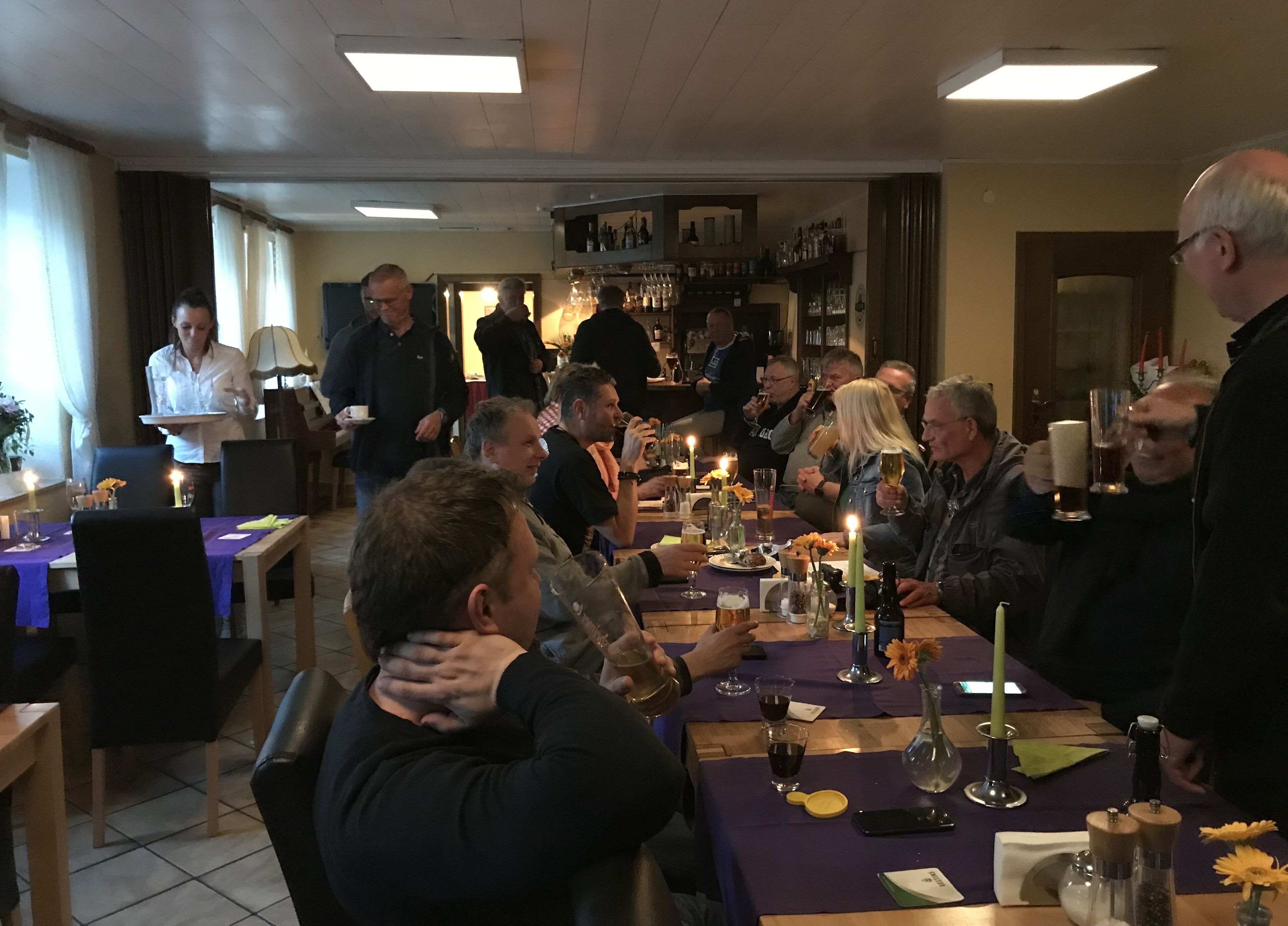 Un gruppo di persone sedute attorno a un tavolo in un ristorante, con candele e bevande.