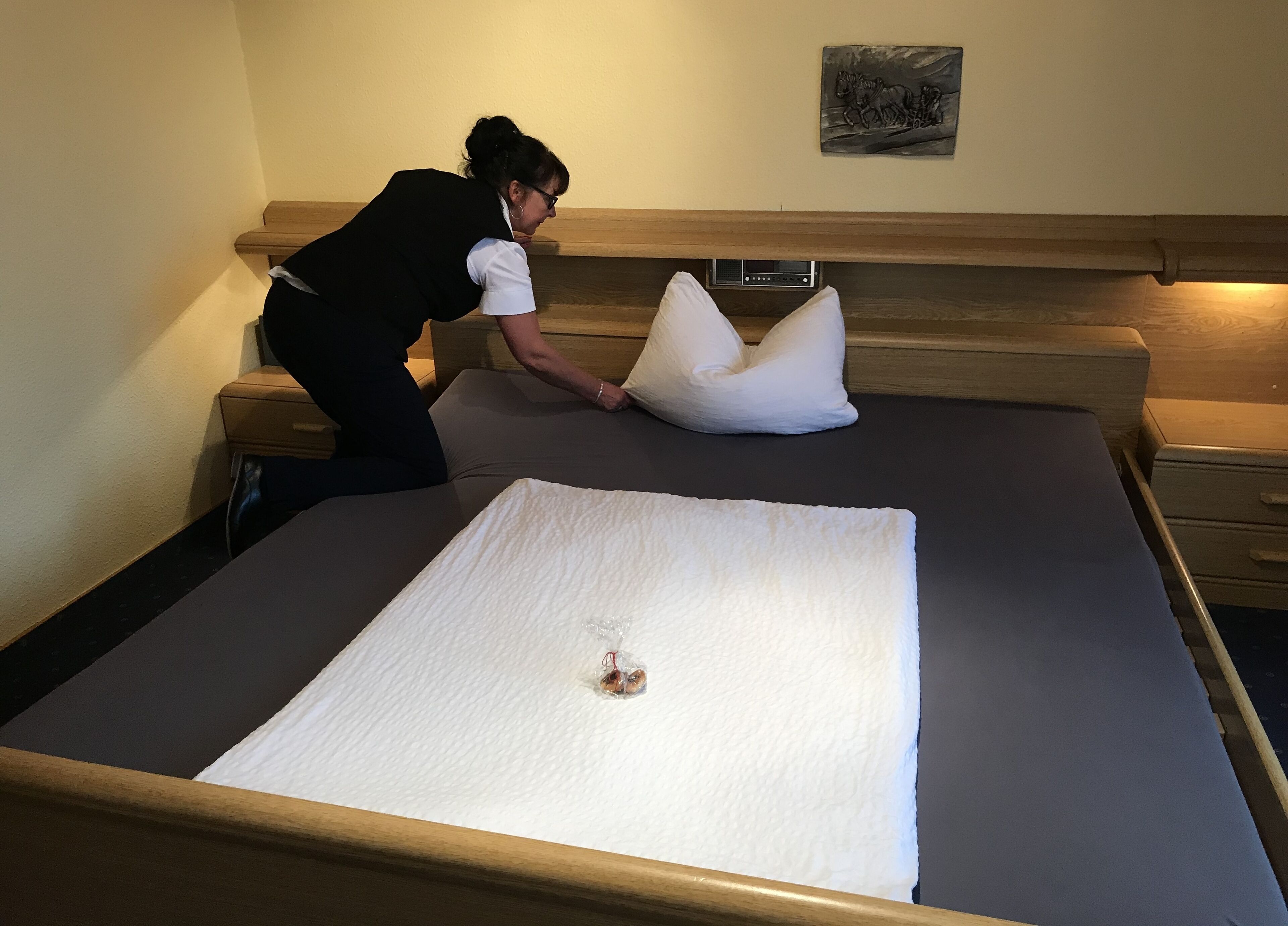 Una cama bien hecha con una almohada blanca y una toalla blanca doblada.