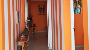Un corridoio con pareti a righe arancioni e bianche, una panca di legno, un tavolino e un quadro appeso al muro.