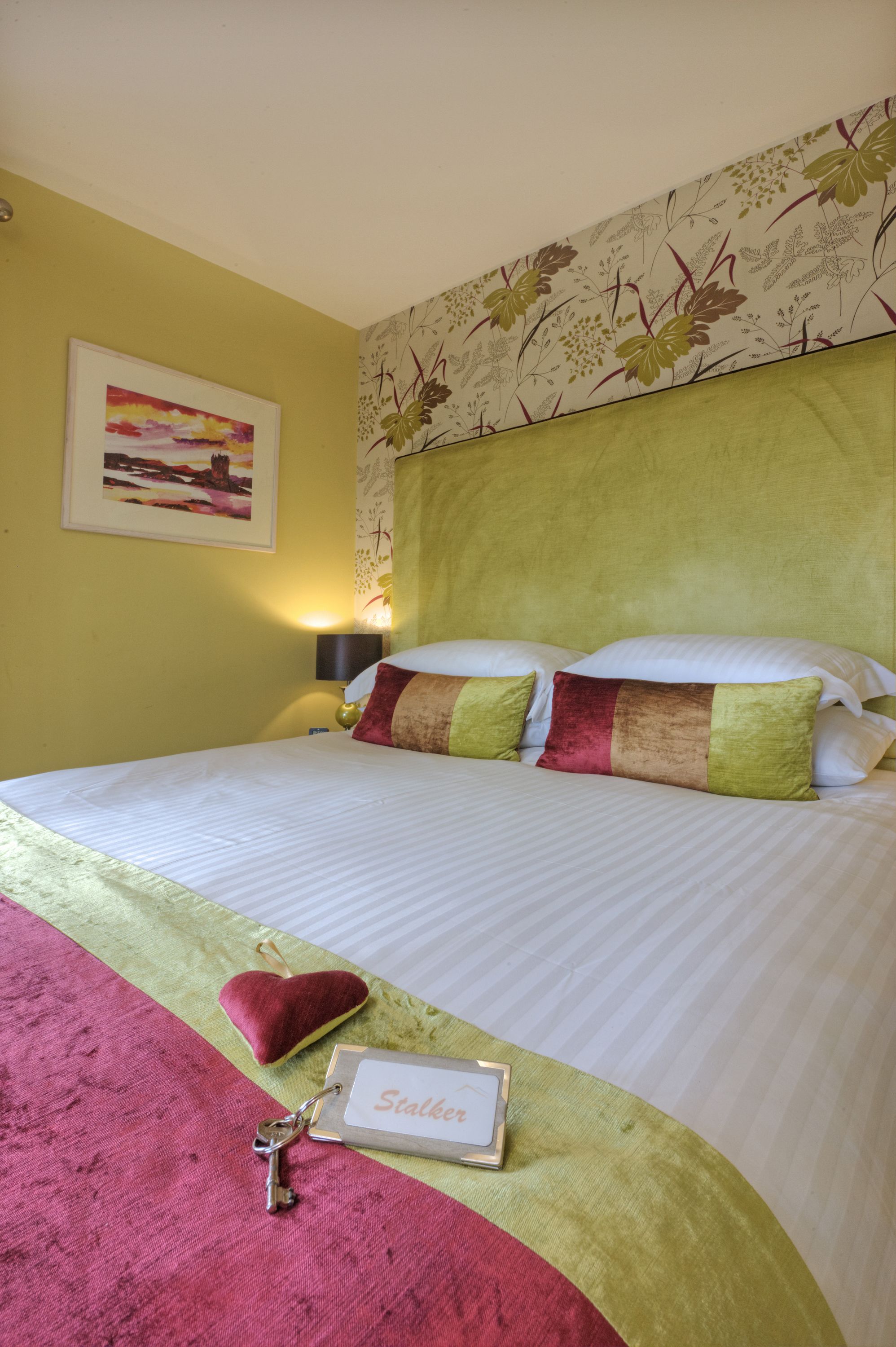 A neatly made bed with a decorative pillow, a key, and a name tag on the bedspread.