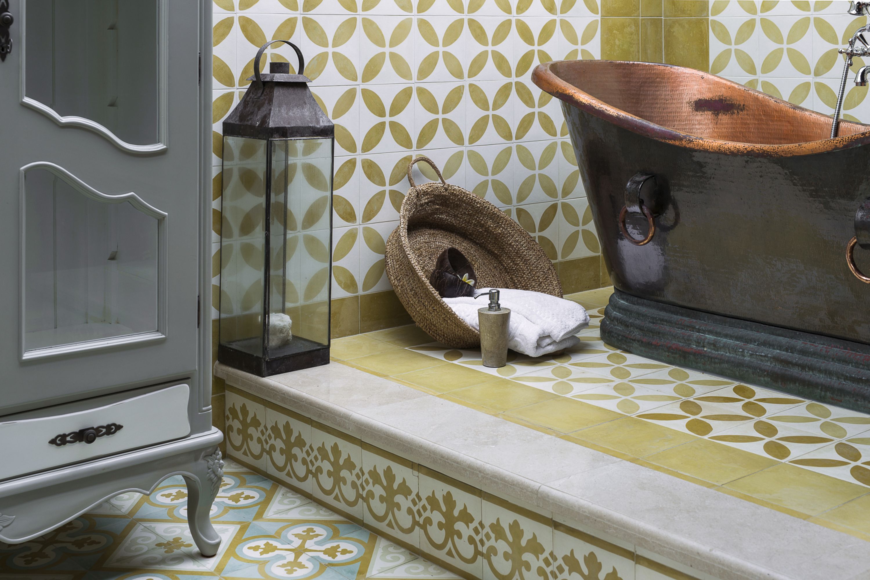 Un baño con bañera, espejo, lámpara y un tapete decorativo.